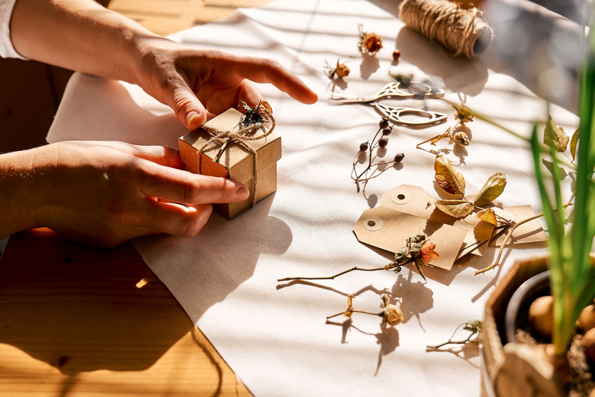 Woman decorating wrapped gifts with recycled paper with dried flowers. Natural aesthetic. Zero waste, plastic free, trendy, handmade gift package.
